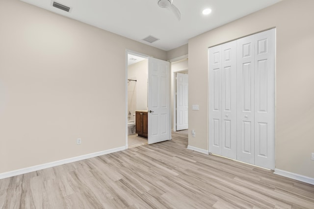 unfurnished bedroom with ensuite bathroom, light hardwood / wood-style floors, and a closet