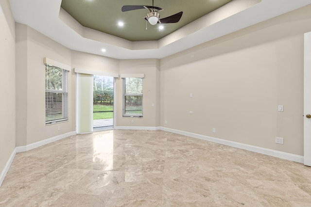 empty room featuring ceiling fan and a tray ceiling