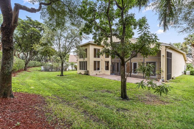 rear view of house with a yard, central AC, and a patio area