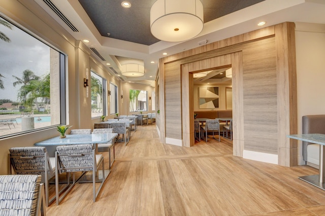 dining area featuring a tray ceiling and light hardwood / wood-style flooring