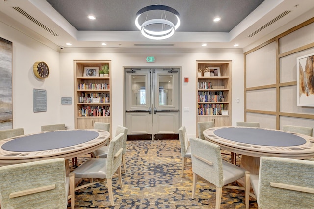 rec room with built in shelves, a tray ceiling, and carpet floors