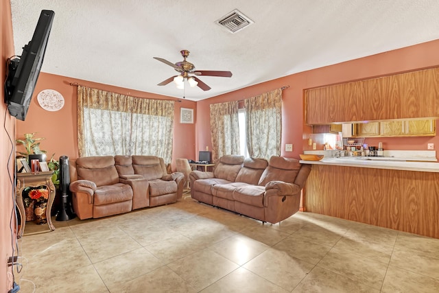 tiled living room featuring ceiling fan and a textured ceiling