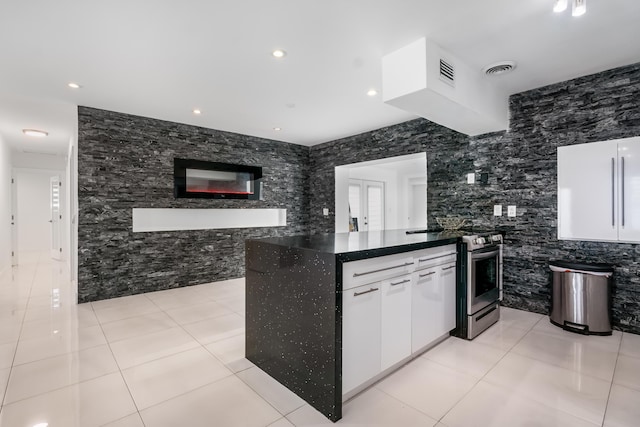 kitchen with white cabinetry, electric range, kitchen peninsula, light tile patterned floors, and tile walls