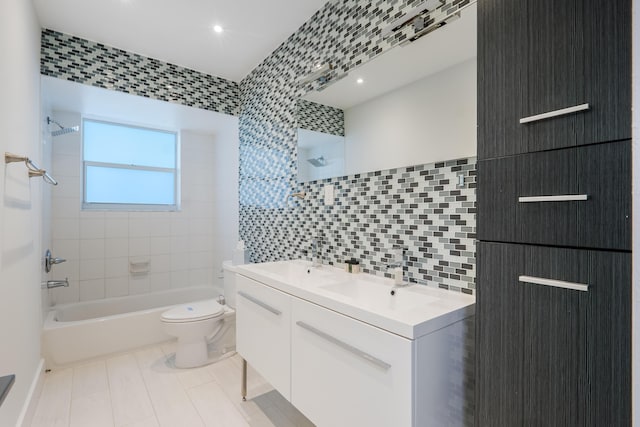 full bathroom featuring toilet, decorative backsplash, vanity, tile walls, and tiled shower / bath