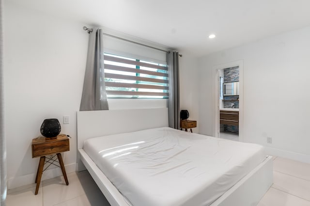 bedroom with ensuite bathroom and light tile patterned floors