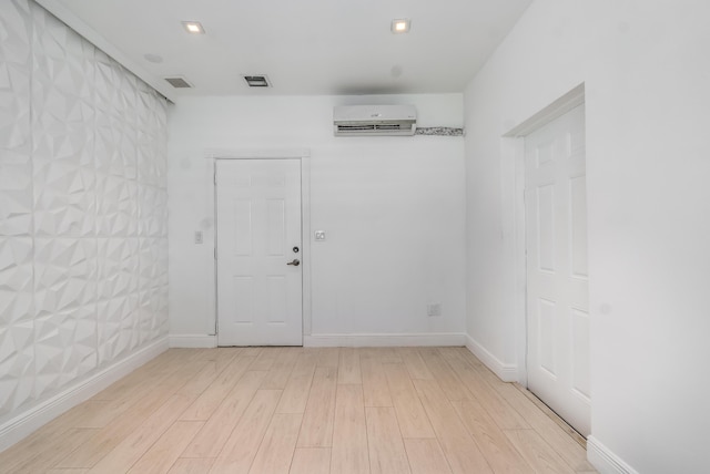 unfurnished room with a wall mounted air conditioner and light hardwood / wood-style flooring