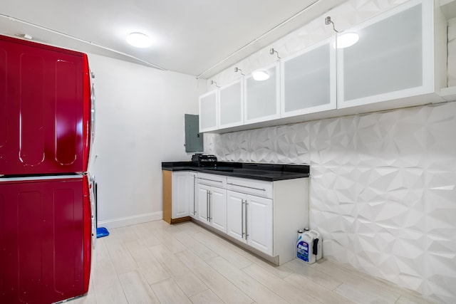 laundry area featuring stacked washer / dryer and electric panel