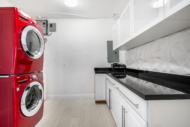 clothes washing area with electric panel, light hardwood / wood-style flooring, and stacked washer and clothes dryer