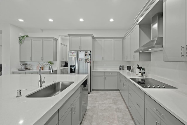 kitchen with a sink, wall chimney exhaust hood, stainless steel appliances, and light countertops