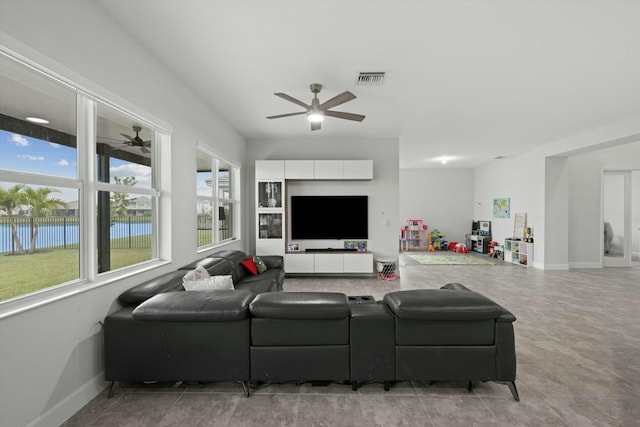 living room with a water view, ceiling fan, visible vents, and baseboards