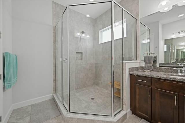 bathroom with a stall shower, tile patterned flooring, vanity, and baseboards