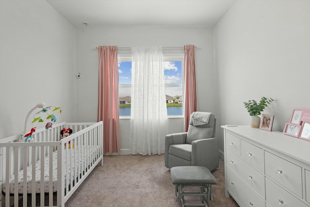 bedroom with light carpet, a nursery area, and a water view