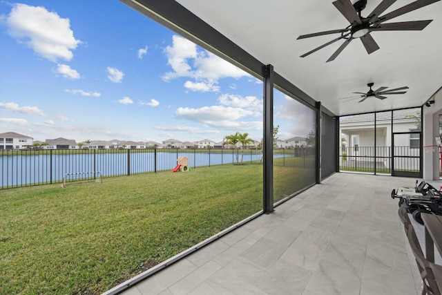 unfurnished sunroom with a ceiling fan, a residential view, and a water view