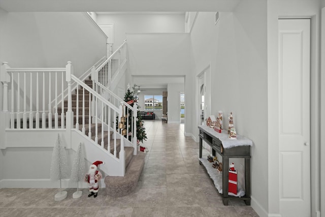 foyer entrance with stairs and baseboards