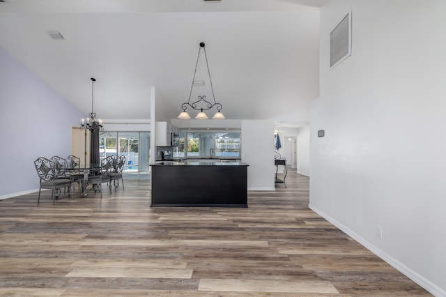 kitchen featuring pendant lighting, wood-type flooring, a high ceiling, and a chandelier