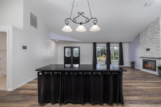 kitchen with a center island, dark hardwood / wood-style flooring, decorative light fixtures, lofted ceiling, and a fireplace