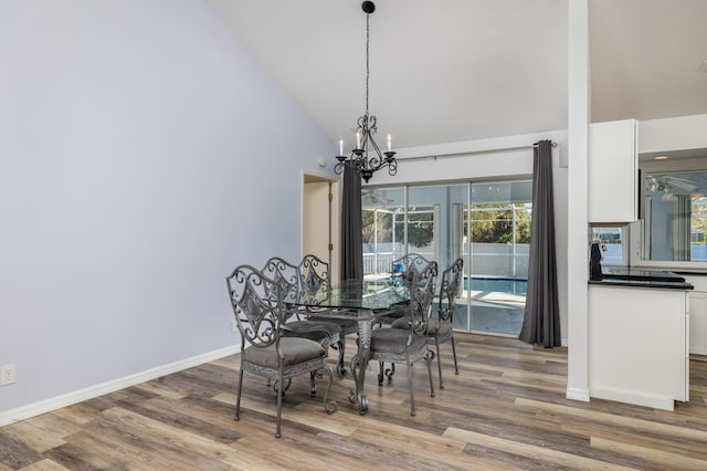 dining room with hardwood / wood-style floors, an inviting chandelier, and high vaulted ceiling