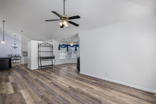 unfurnished living room with hardwood / wood-style flooring, ceiling fan with notable chandelier, and vaulted ceiling