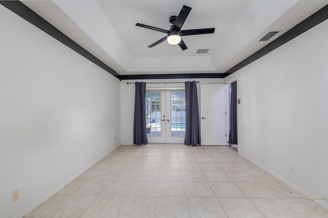 unfurnished room with a raised ceiling, ceiling fan, french doors, and light tile patterned floors