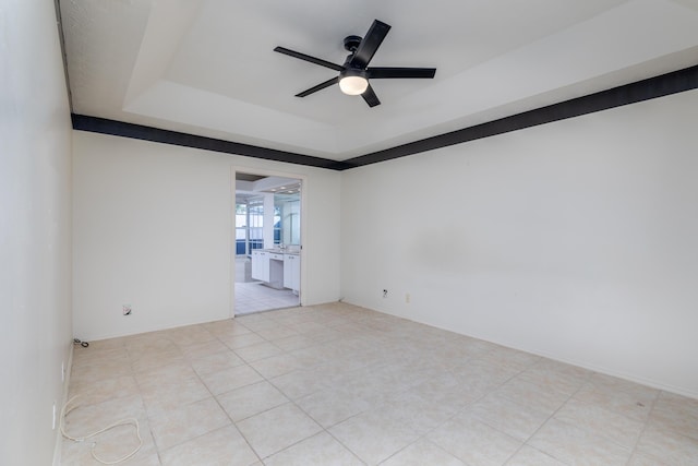 tiled spare room featuring a tray ceiling and ceiling fan