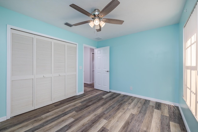 unfurnished bedroom with ceiling fan, dark wood-type flooring, and a closet