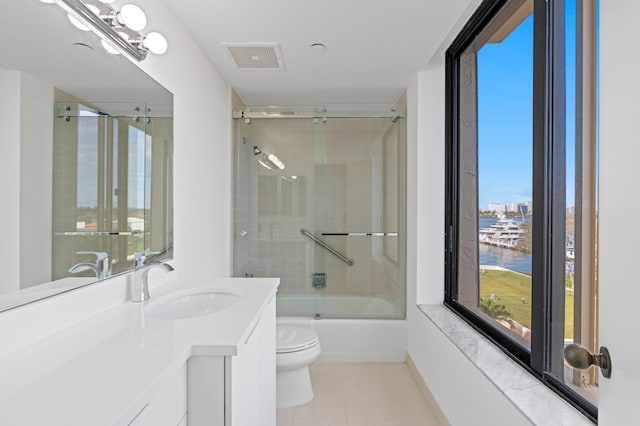 full bathroom with combined bath / shower with glass door, vanity, a water view, and toilet