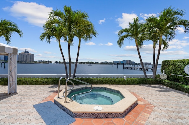 view of swimming pool featuring a patio area, an in ground hot tub, and a water view