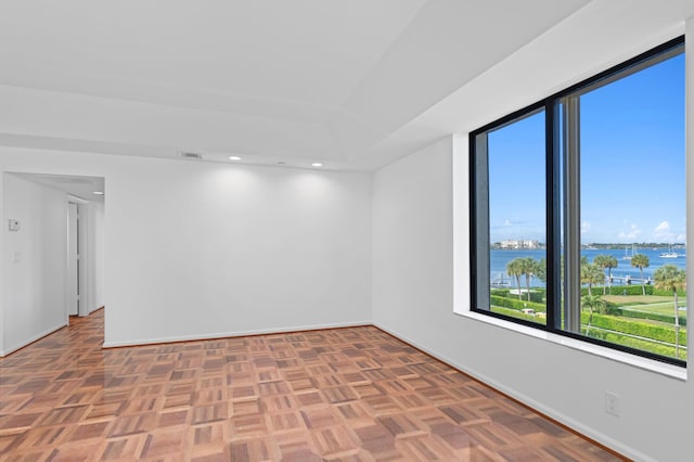 unfurnished room featuring a water view and parquet floors