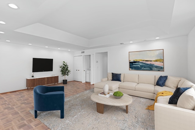 living room featuring parquet flooring and a tray ceiling