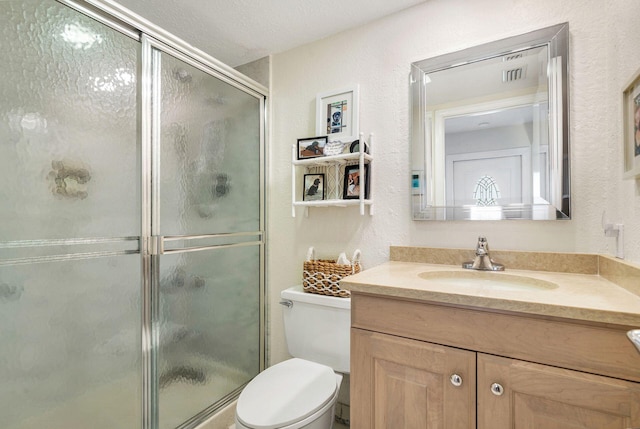 bathroom with vanity, toilet, an enclosed shower, and a textured ceiling