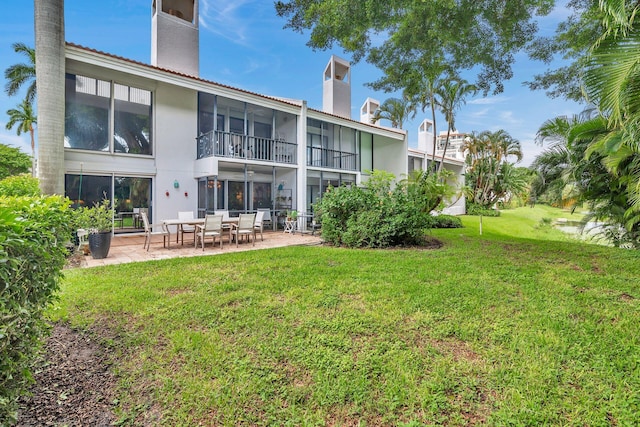 back of property with a yard and a patio