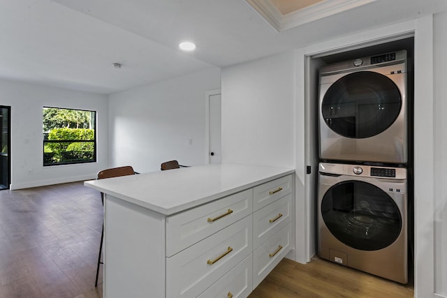 washroom with crown molding, light hardwood / wood-style flooring, and stacked washer and clothes dryer