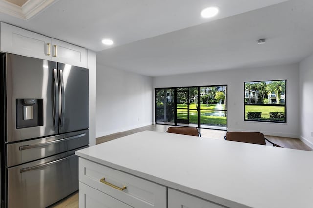 kitchen with stainless steel fridge, white cabinets, and light wood-type flooring