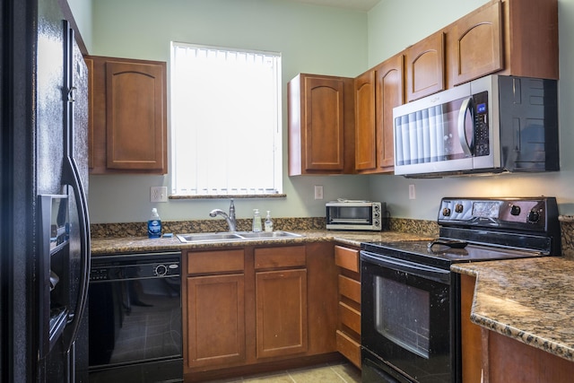 kitchen featuring light tile patterned floors, sink, dark stone counters, and black appliances