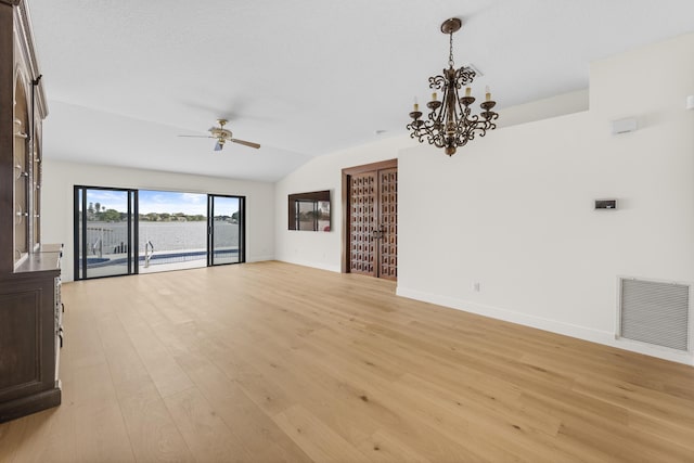 unfurnished living room featuring lofted ceiling, light hardwood / wood-style floors, and ceiling fan with notable chandelier