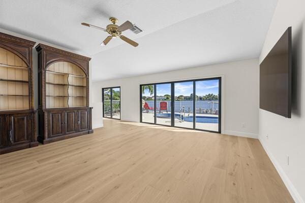 unfurnished living room with light wood-type flooring, vaulted ceiling, and ceiling fan