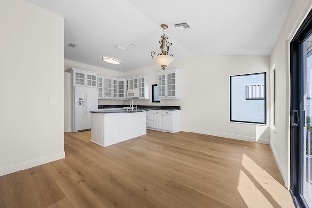 kitchen featuring white appliances, a kitchen island with sink, pendant lighting, light hardwood / wood-style flooring, and white cabinets