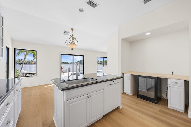 kitchen with white cabinetry, dishwasher, sink, decorative light fixtures, and light wood-type flooring