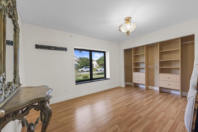 bedroom featuring a textured ceiling, light wood-type flooring, and a closet