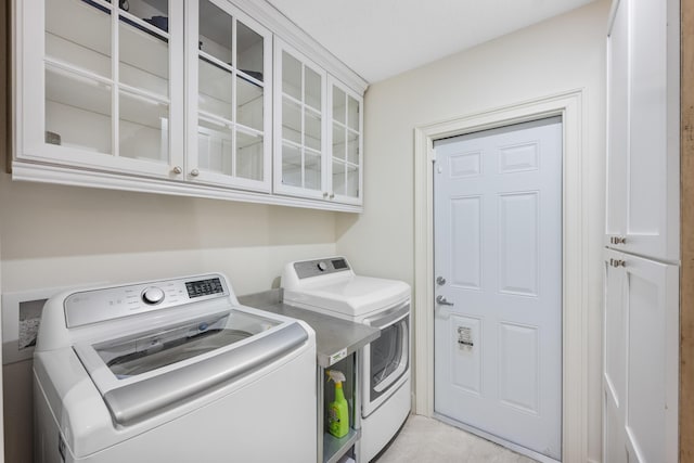 laundry room featuring washer and dryer, cabinets, and light tile patterned floors