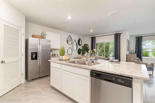 kitchen with sink, light tile patterned floors, an island with sink, white cabinets, and appliances with stainless steel finishes