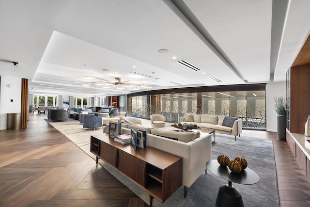 living room with parquet flooring, a tray ceiling, and ceiling fan