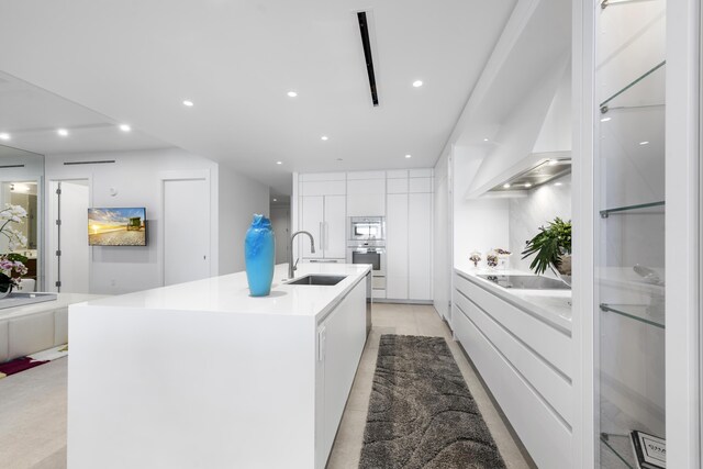 kitchen with stainless steel oven, sink, a spacious island, black electric stovetop, and white cabinets