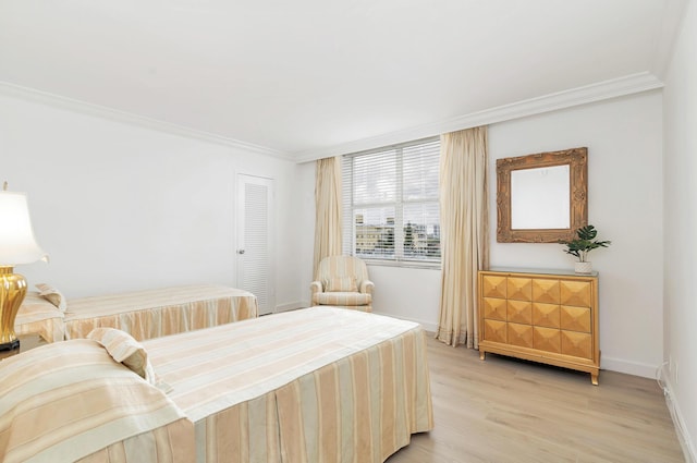 bedroom with light hardwood / wood-style floors, ornamental molding, and a closet