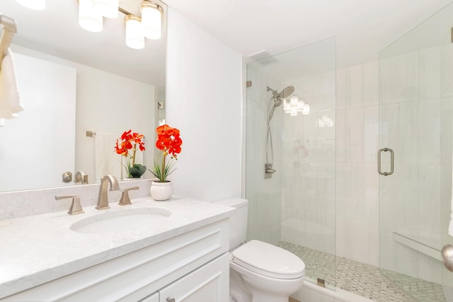 bathroom featuring a shower with door, vanity, and toilet