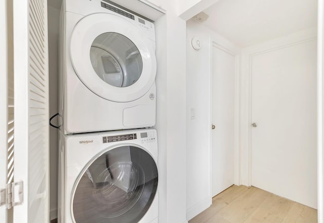 laundry room with stacked washer and dryer and light hardwood / wood-style flooring