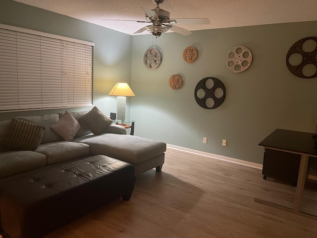 living room featuring ceiling fan, a textured ceiling, and light hardwood / wood-style floors