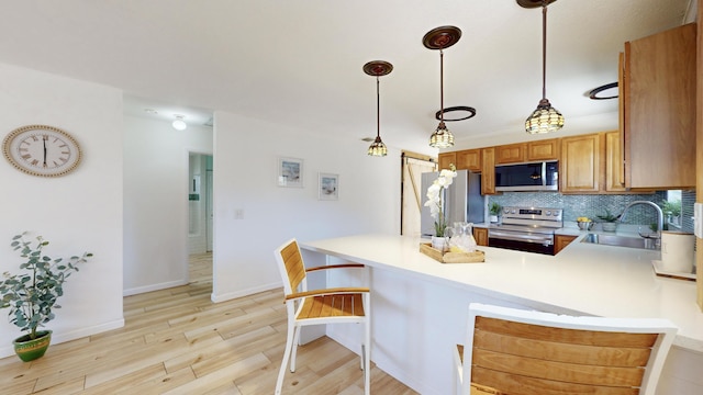 kitchen with kitchen peninsula, sink, decorative light fixtures, and appliances with stainless steel finishes