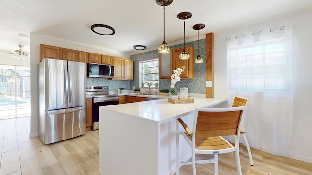 kitchen with kitchen peninsula, appliances with stainless steel finishes, backsplash, sink, and hanging light fixtures