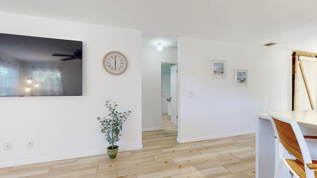 interior space featuring a barn door, ceiling fan, and light hardwood / wood-style floors